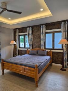 a bedroom with a wooden bed and two windows at Baan Khun Pra Chiang Mai Near Chiang mai Airport in Chiang Mai