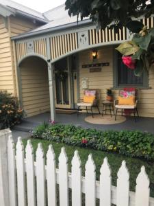 a white fence in front of a house with chairs at Wyreema, Heritage Cottage in Geelong West
