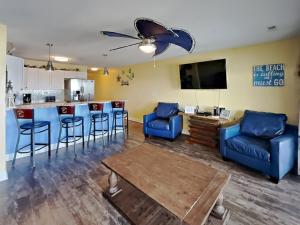 a living room with a kitchen and a bar with blue chairs at Put-in-Bay Waterfront Condo #206 in Put-in-Bay