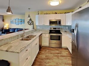a kitchen with white cabinets and stainless steel appliances at Put-in-Bay Waterfront Condo #206 in Put-in-Bay