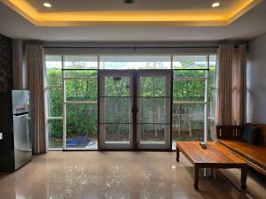 a living room with sliding glass doors and a wooden table at Baan Khun Pra Chiang Mai Near Chiang mai Airport in Chiang Mai