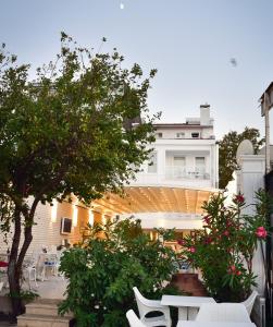 un patio con sedie bianche e alberi e un edificio di Büyükada Port Hotel a Büyükada