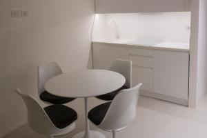 a white kitchen with a white table and chairs at Solo per Noi Apartment in Siena