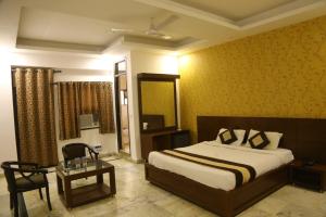 a bedroom with a bed and a chair and a table at Rockwood Inn in Faridabad +18 photos