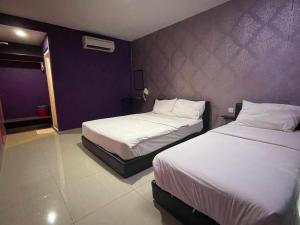 a bedroom with two beds and a purple wall at Parc Hotel Pelangi Damansara in Kuala Lumpur