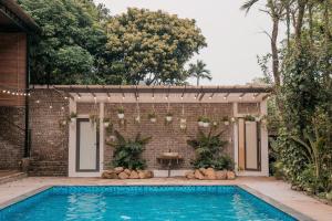 a swimming pool in a backyard with a brick wall at Sunny Camping Sóc Sơn in Sóc Sơn