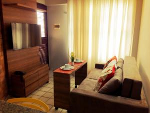 een woonkamer met een bank en een tafel bij Costeira Praia - Belo Flat in Natal
