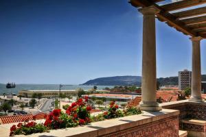 a balcony with red flowers and a view of a city at Casa Miradouro Apartments in Setúbal