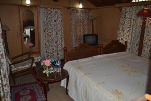 a bedroom with a large bed and a television at Houseboat Young Kabul in Srinagar