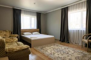 a bedroom with a bed and a couch and a chair at Hotel Дар-Ай in Kostanay