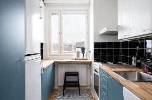 a kitchen with blue cabinets and a sink and a stool at 2 Bedroom apartment with free parking and airconditioning in Kuopio