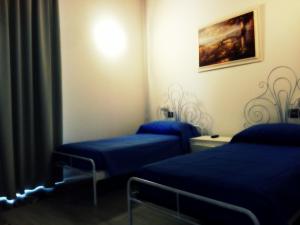 ターラントにあるB&B San Francescoのブルーシーツ付きの客室内のベッド2台