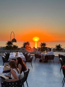 a group of people sitting at tables on a patio with the sunset at Comfort Suites in Golem