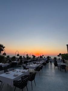 a restaurant with tables and chairs with the sunset in the background at Comfort Suites in Golem +176 photos