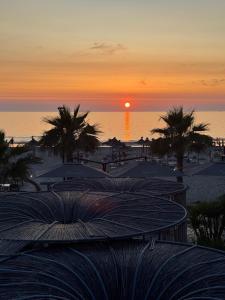 a sunset on a beach with palm trees and the ocean at Comfort Suites in Golem