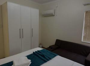 a small bedroom with a bed and a couch at P & S Executive Home in Maseru +3 photos