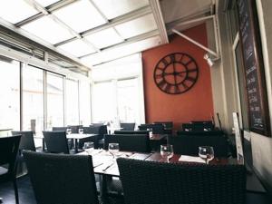 a dining room with tables and chairs and a clock on the wall at Hôtel Brasserie Le Lion d'Or in Meximieux