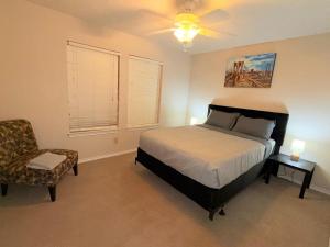 リチャードソンにあるSpacious 2BR Townhomeのベッドルーム1室(ベッド1台、椅子、シーリングファン付)