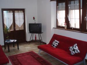 ダンバッハ・ラ・ヴィルにあるGite Alizeのリビングルーム(赤いソファ、テレビ付)