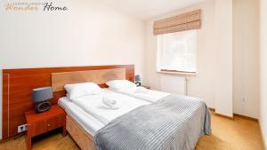 ein Schlafzimmer mit einem großen Bett mit einem hölzernen Kopfteil in der Unterkunft Wonder Home - Apartamenty blisko stoku, centrum i aquparku in Karpacz