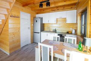a kitchen with white cabinets and a wooden wall at Domek nad samym jeziorem sauna jacuzzi in Ełk