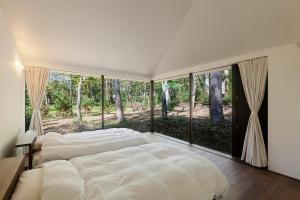 a bedroom with a large bed and large windows at Mori no Hanare in Karuizawa +69 photos