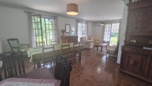 un salon avec une table, des chaises et des fenêtres dans l'établissement Verte Rive – Maison climatisée en bord de Dordogne, à Cénac-et-Saint-Julien
