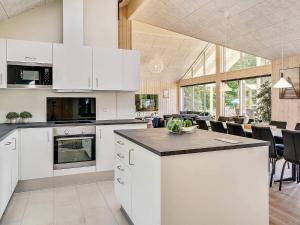 a kitchen with white cabinets and a dining room at Luxury Pool Villa in Vejby - By Traum Ferienwohnungen in Vejby +10 photos