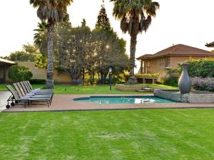 a yard with two benches and a pool with palm trees at ANEW Hotel Witbank Emalahleni in eMalahleni