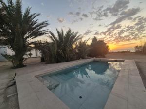 a swimming pool with a sunset in the background at Cortijo El Guarda in Almería
