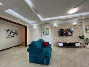a living room with a blue chair and a tv at Antalya Epic stays in Mombasa