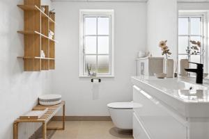 a white bathroom with a toilet and a sink at Modern Family House Near Købingsmark Beach in Nordborg +22 photos