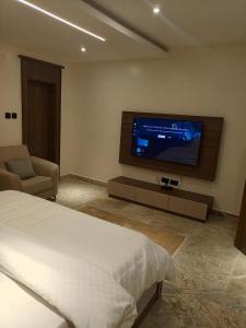 a bedroom with a bed and a flat screen tv at The Iconic Place in Garki
