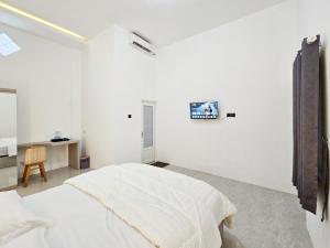 a white bedroom with a bed and a desk at Dhoriz Homestay Syariah RedPartner at Kampung Inggris Pare in Pare +49 photos