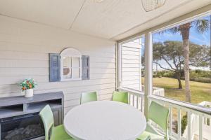 eine Veranda mit einem weißen Tisch und Stühlen und einem Kamin in der Unterkunft Beach Club Villa 27 - Oceanview Walkout by Beach and Pool in Isle of Palms