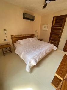 Brisas de ZicatelaにあるCondominios Punta Morelosのベッドルーム(大きな白いベッド、ファン付)