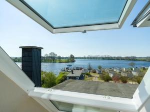 Una ventana del ático con vista al agua en Spacious Ensemble Hecht Right On The Eider River, en Süderstapel