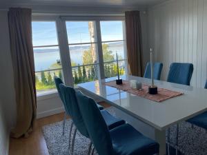 Una mesa de comedor con sillas y una gran ventana. en Nice Family Friendly apartment 2 bed Rooms with sea view located in Nordstrand for 5 guests with a garden and grill with sea view just beside the apartment, en Oslo