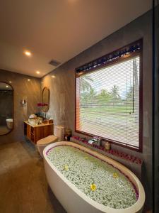 baño con bañera grande y ventana en Ascarya Ubud, en Ubud
