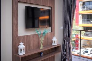 una televisione su un muro con un vaso su uno scaffale di Chic 1BR Condo Steps from Nai Harn S311 a Nai Harn Beach