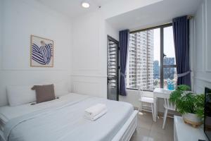 a white bedroom with a bed and a desk and a window at DFour River Gate Deluxe Apartment by the River in Ho Chi Minh City