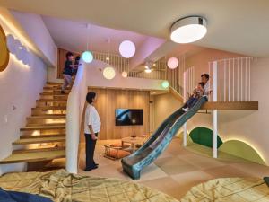 a child on a slide in a room with people at Hotel New Wakasa in Nara