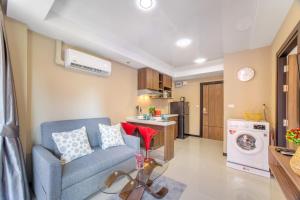 a living room with a blue couch and a kitchen at LUMA Condo 1BR Open View NBC Nai Harn in Rawai Beach