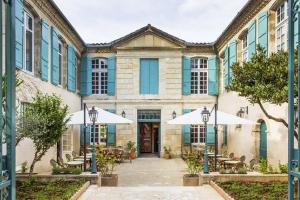 - une vue sur l'extérieur d'un bâtiment avec des tables et des parasols dans l'établissement Les Trois Lys, à Condom