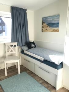 une petite chambre avec un lit et une chaise dans l'établissement 'DÜNENBLICK 2' am Pirolatal, à Langeoog