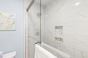 a white bathroom with a shower and a tub at Lagoon Villa 25 - Heart of Wild Dunes, Quick Walk to Beach in Isle of Palms +16 photos