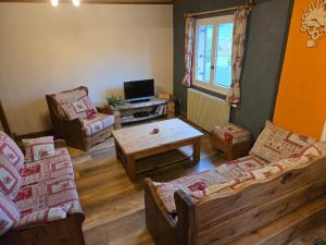 a living room with couches and a table and a tv at Gîte Le Lac à La Dame in Foncine-le-Bas
