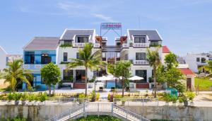 a building on the beach with palm trees in front at CocoPalm Hoi An River Beach in Hoi An
