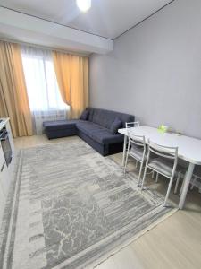 a living room with a couch and a table at Квартира в новом доме недалеко от центра Бишкека in Bishkek