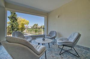 a living room with chairs and a table and a large window at Hesperides Gardens D203 in Ktima